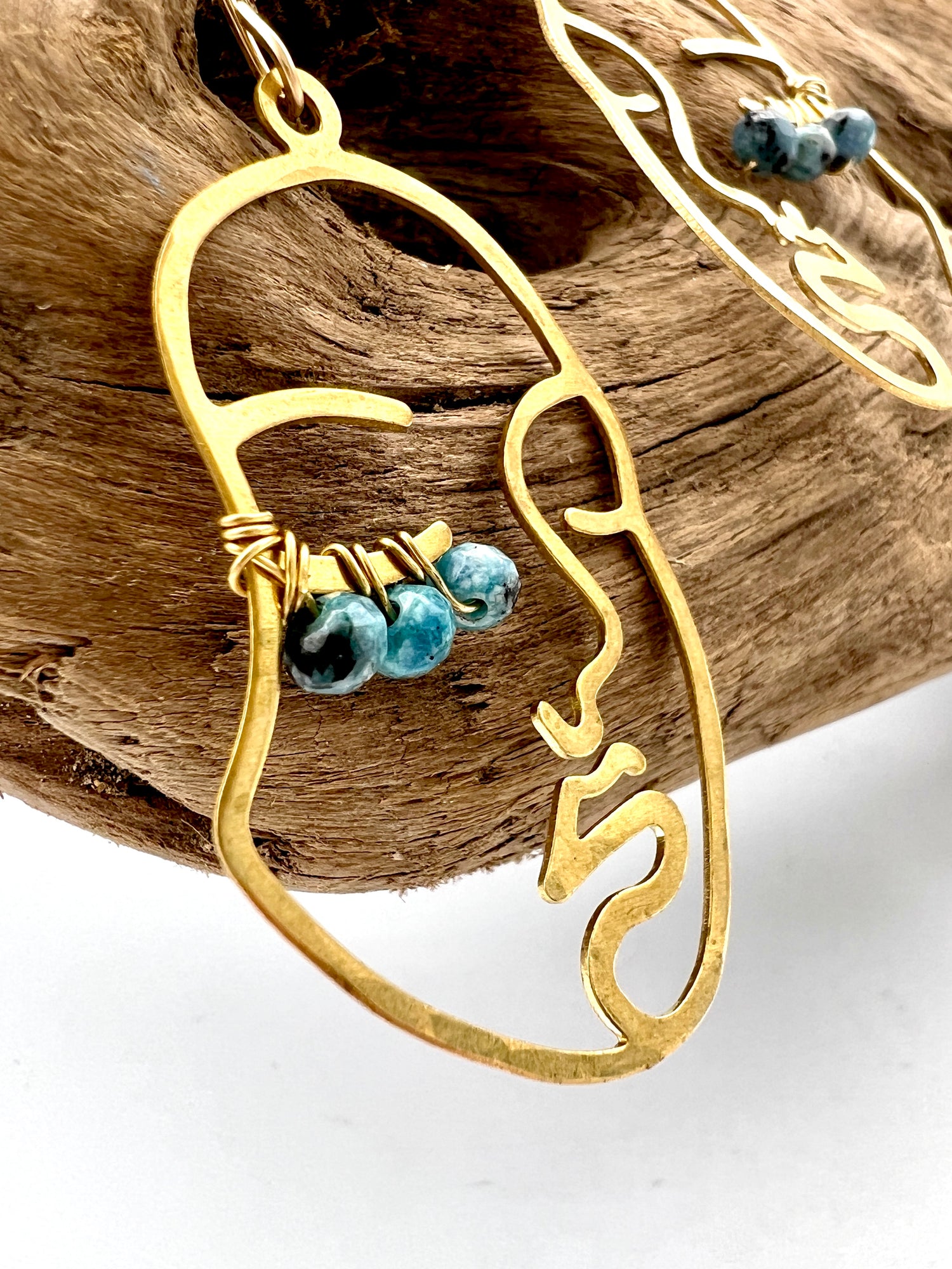 up close image of Hammered brass face earrings with blue wired beaded lashes in customizable colors. 14k gold-filled ear wires, lightweight and full of personality