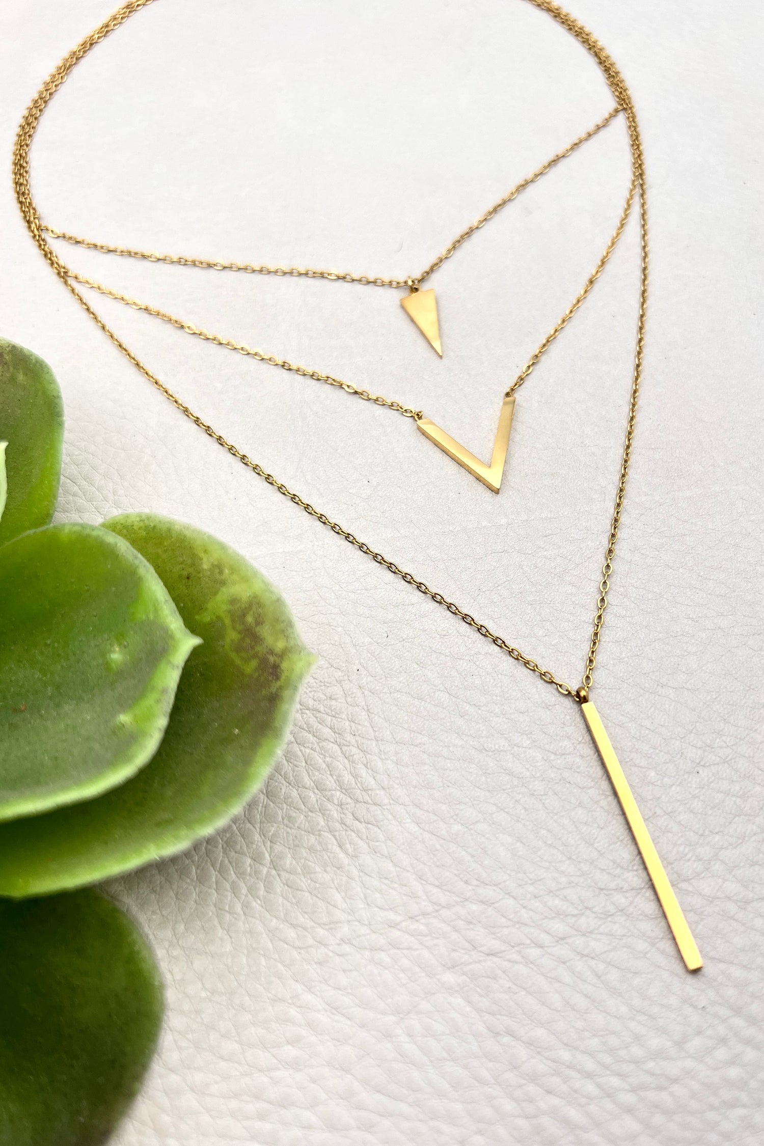 golden layered necklace with triangle, V shape and spike pendants