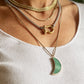 Woman wearing layered gold and silver chunky necklaces with green moon and carabiner 