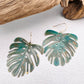 Vivacious modern boho statement jewelry – handcrafted blue patina monstera leaf earrings, a bold and artistic design from Real to the Roots Jewelry. 