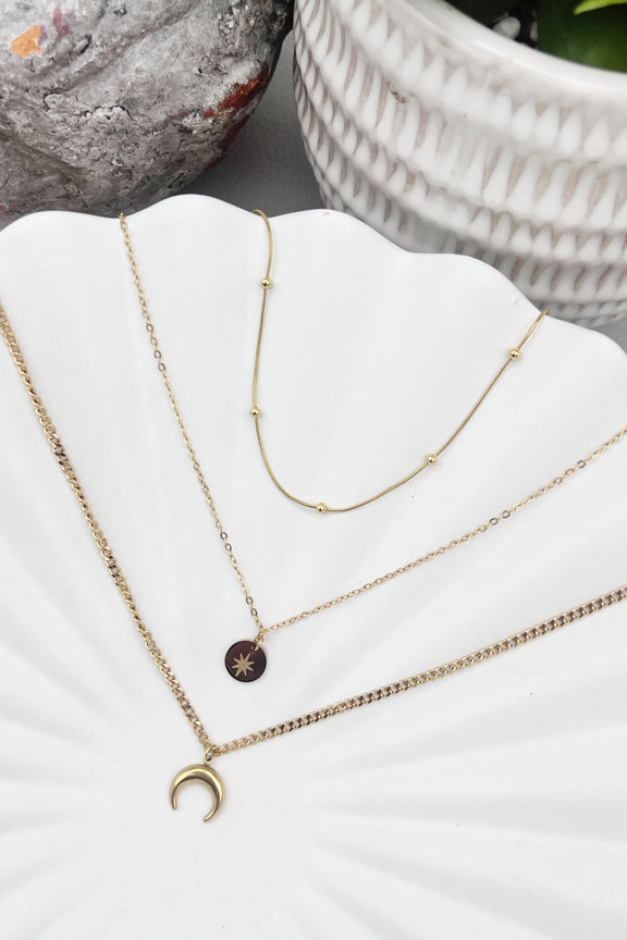 Triple-layered 14k gold-plated stainless steel necklace with a crescent moon, sun coin, and satellite chain. Waterproof and tarnish-resistant.