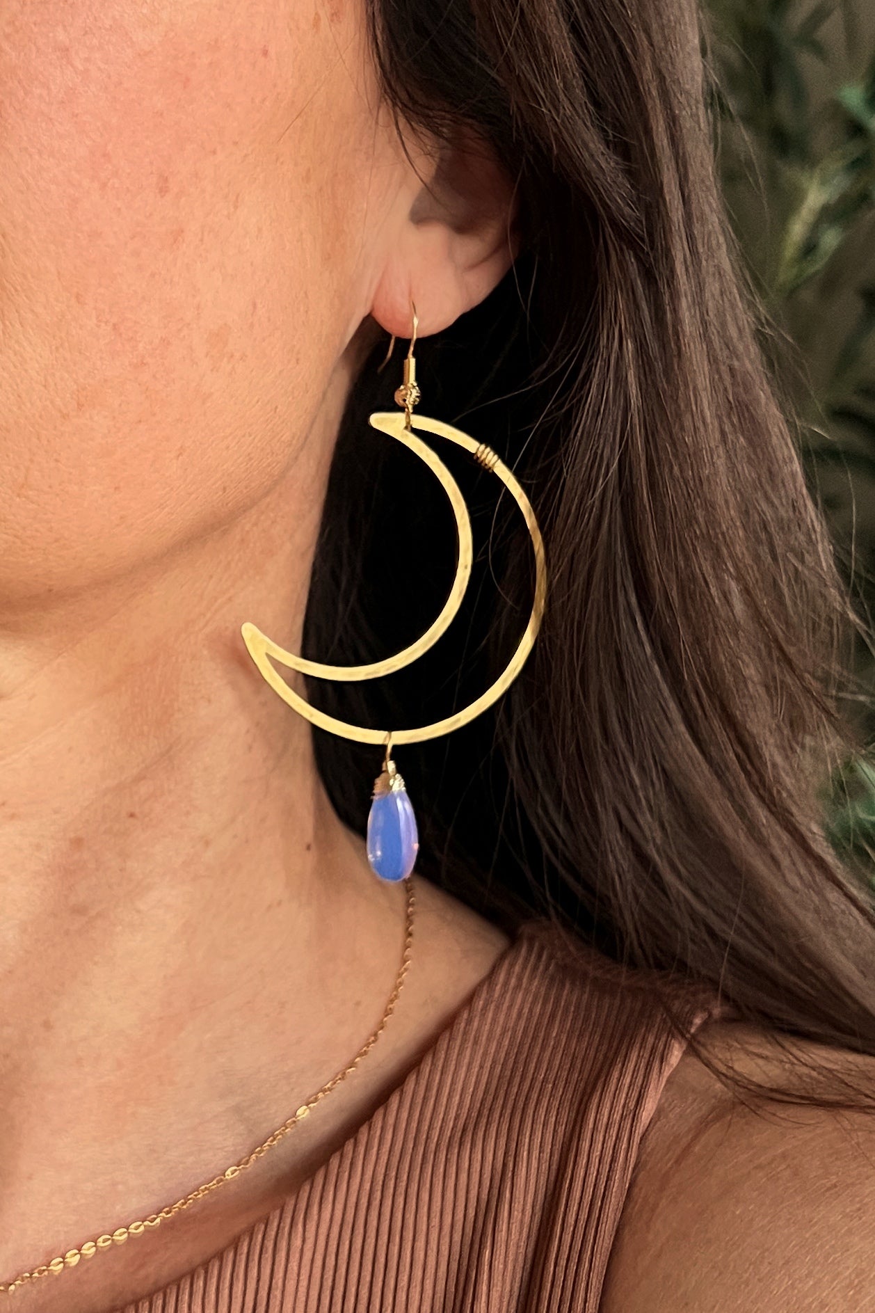 woman wearing a crescent moon earring with a wired gem
